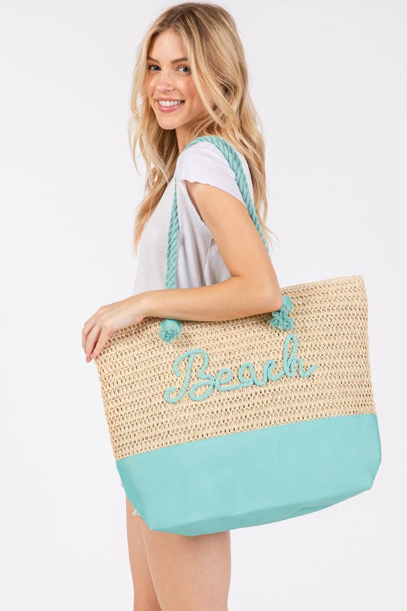 Smiling woman carrying a woven straw tote bag with aqua rope handles and "Beach" embroidered in aqua script, perfect for summer beach days.
3/3
Smiling woman carrying a woven straw tote bag with aqua rope handles and "Beach" embroidered in aqua script, perfect for summer beach days.
3/3