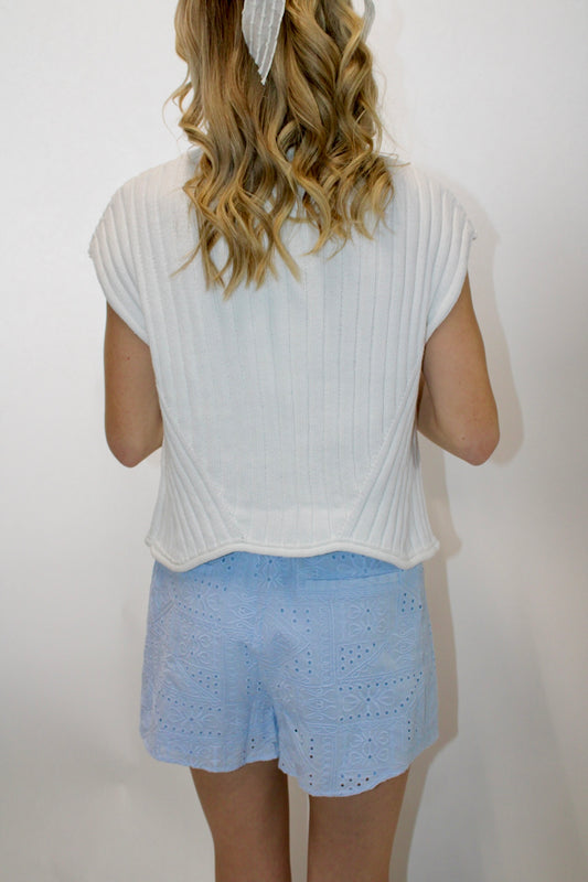 Back view of Ivory ribbed cap sleeve knit top with subtle sculpted hem styled with a light blue skort