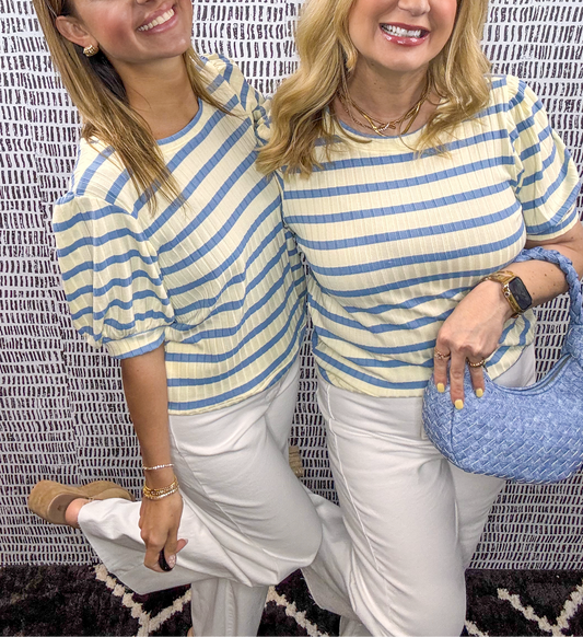 Two women wearing butter yellow and blue striped puff sleeve tops paired with white pants and gold jewelry – light and airy spring or summer outfit inspiration