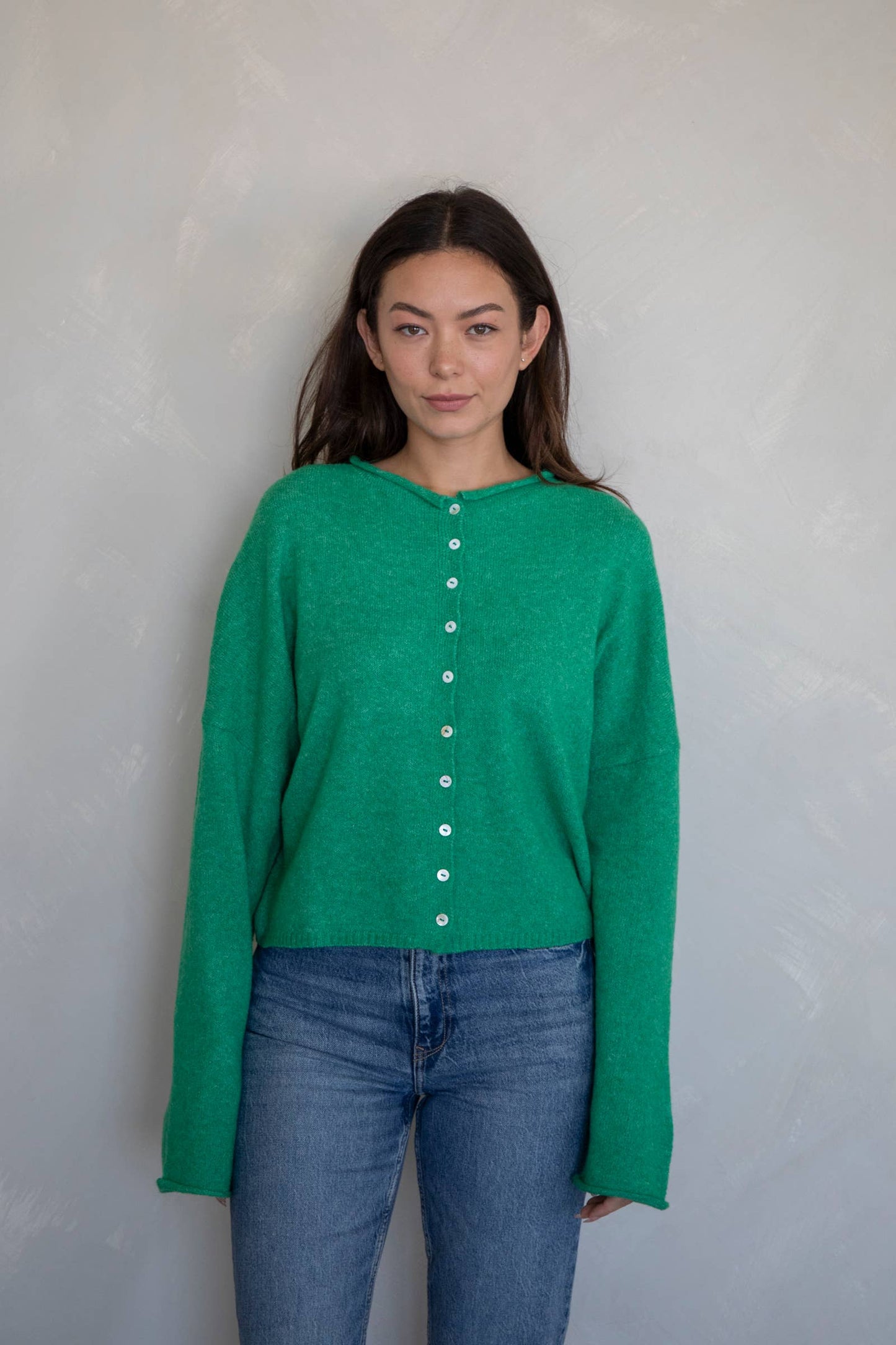 Woman wearing an emerald green button-down lightweight knit sweater cardigan with long sleeves and relaxed fit, perfect for spring layering