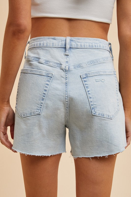Back view of high-rise light wash denim shorts with frayed hem, flattering summer style for women