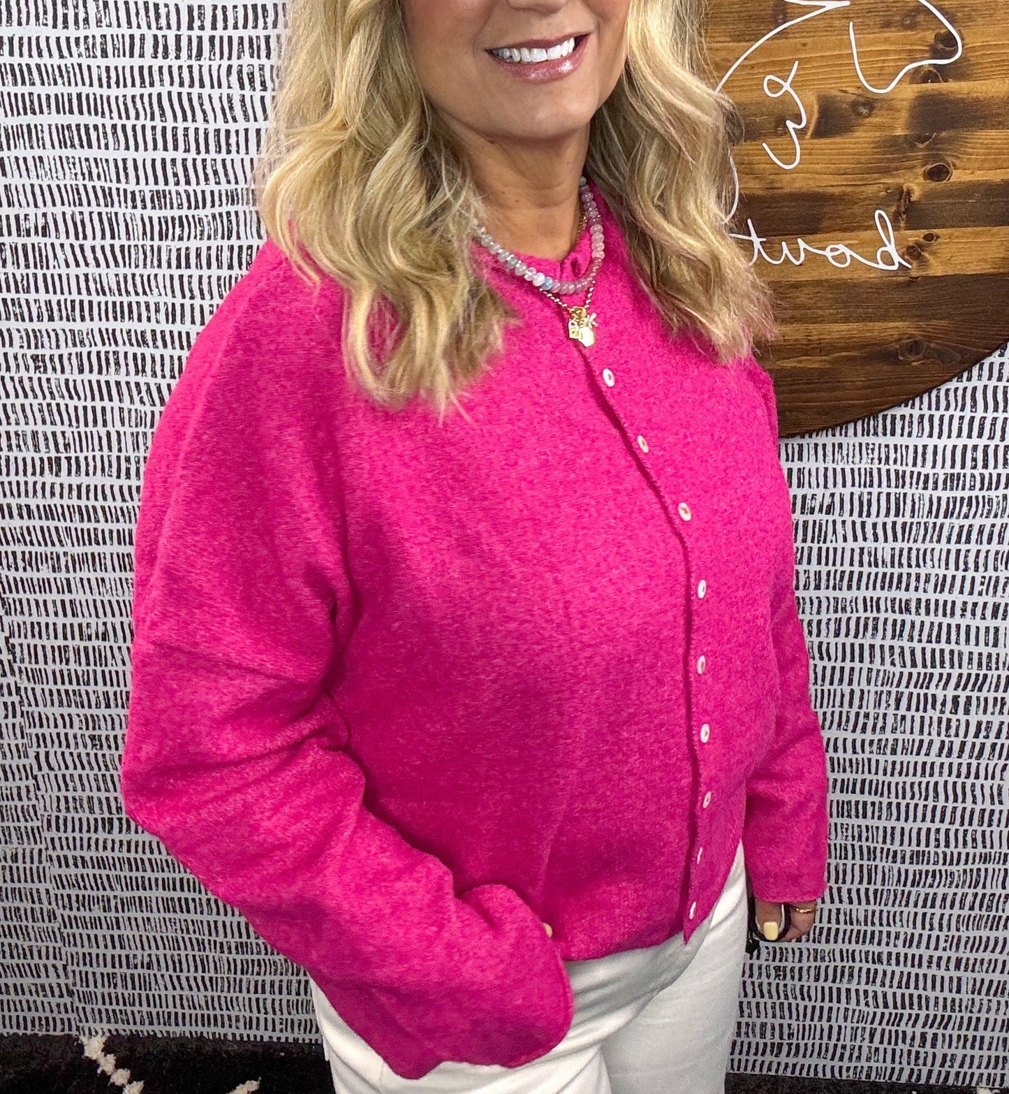 Model wearing hot pink button-down cardigan with pearl buttons, styled with white pants for a vibrant, cozy look – Erin Rose Boutique