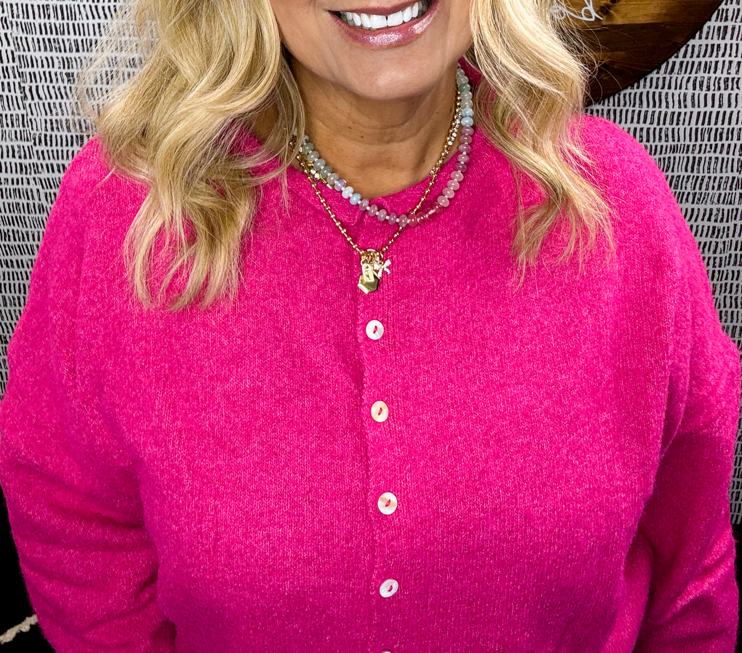Woman wearing a hot pink button-up piper cutie cardi cardigan with layered gold and beaded necklaces – bold and vibrant sweater style for women