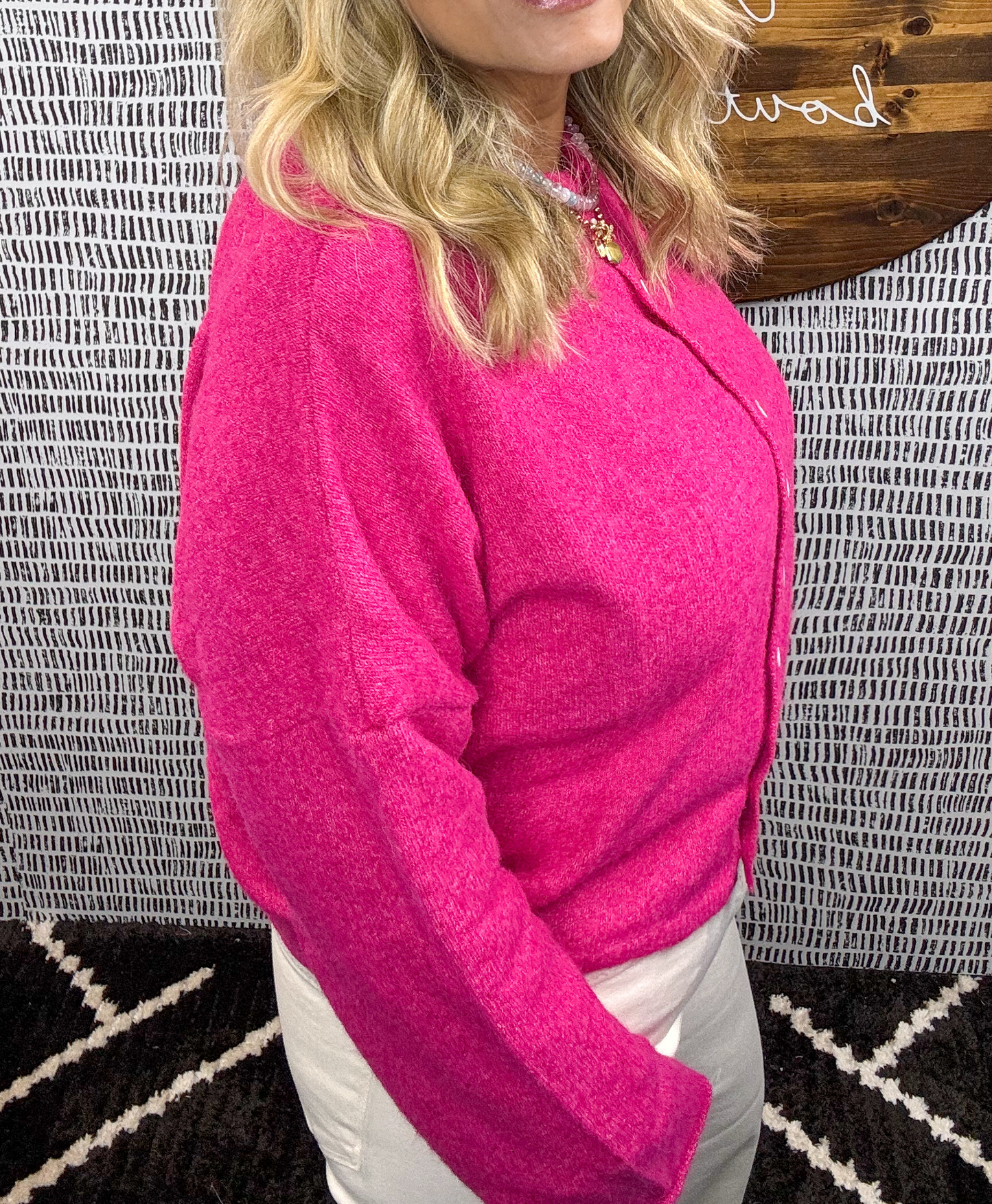 Side view of a woman wearing a hot pink button-up cardigan paired with light pants – bold and cozy women’s sweater perfect for layering