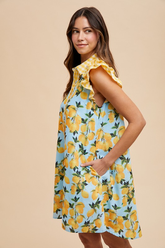 Woman wearing lemon print dress with yellow gingham ruffle sleeves and side pockets