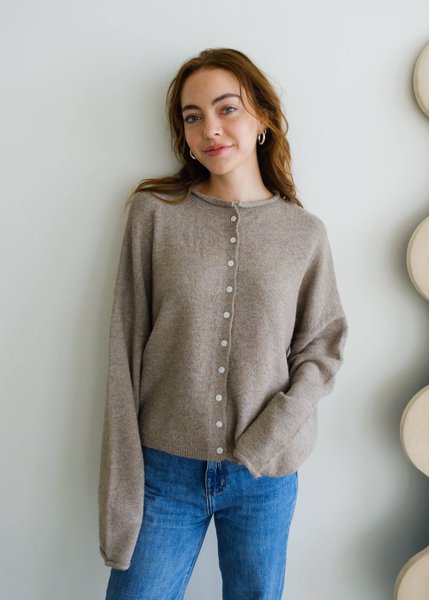 Woman wearing a lightweight mocha button-down Piper cardigan sweater styled with denim jeans, perfect for layering in any season