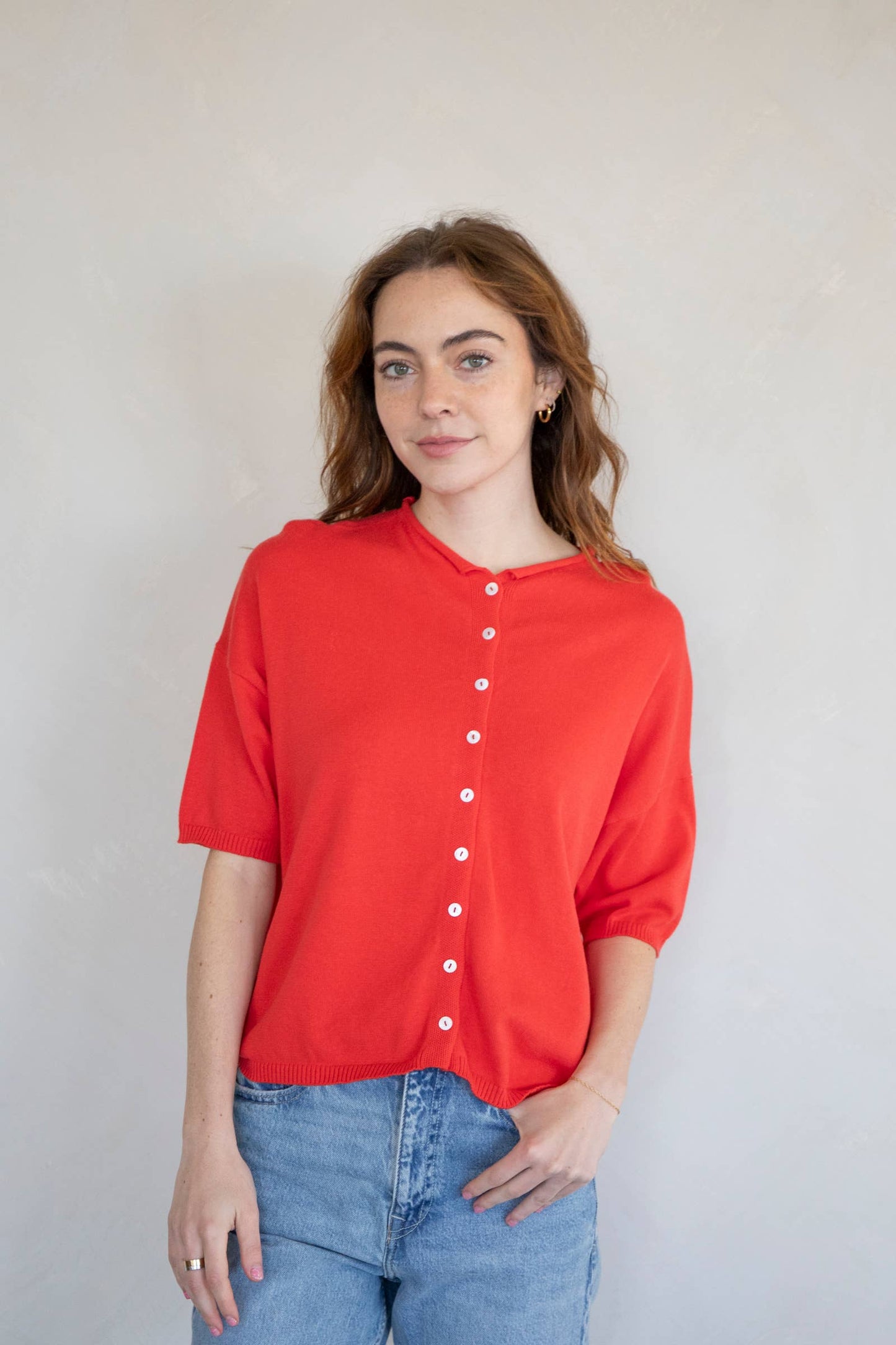 Red short sleeve button-up cardigan knit top for women styled casually with jeans; lightweight and relaxed fit sweater perfect for everyday wear.