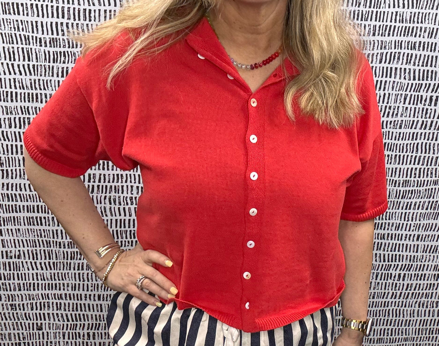 Woman wearing a red short sleeve button-up Cardi knit top paired with navy and white striped shorts – casual summer outfit idea for women