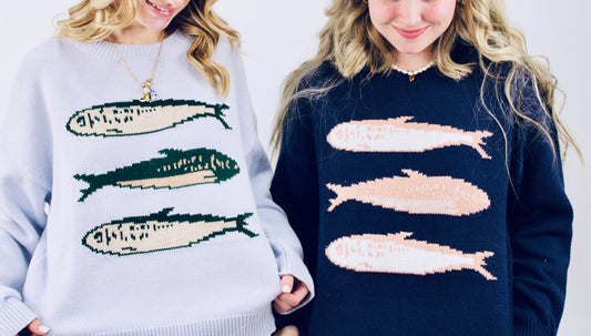 Two people wearing sweaters with fish patterns on a white background