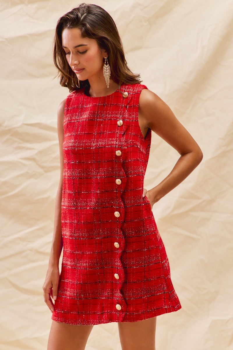 Woman wearing a red plaid dress with buttons on a beige background