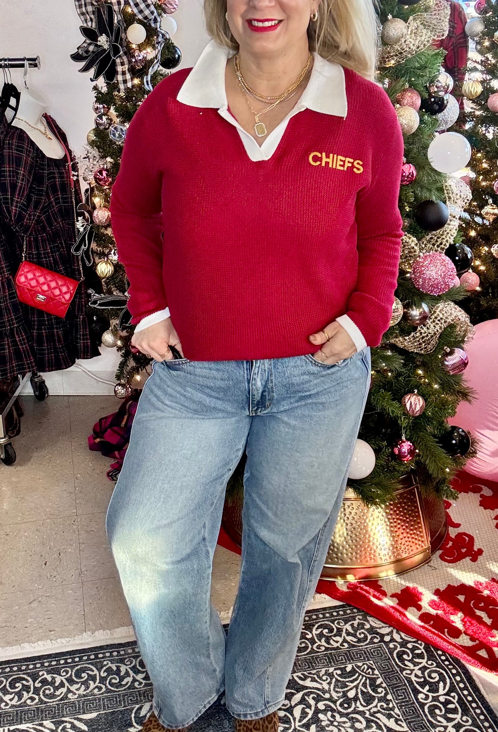Person wearing a red sweater with 'CHEFS' text in front of a decorated Christmas tree.