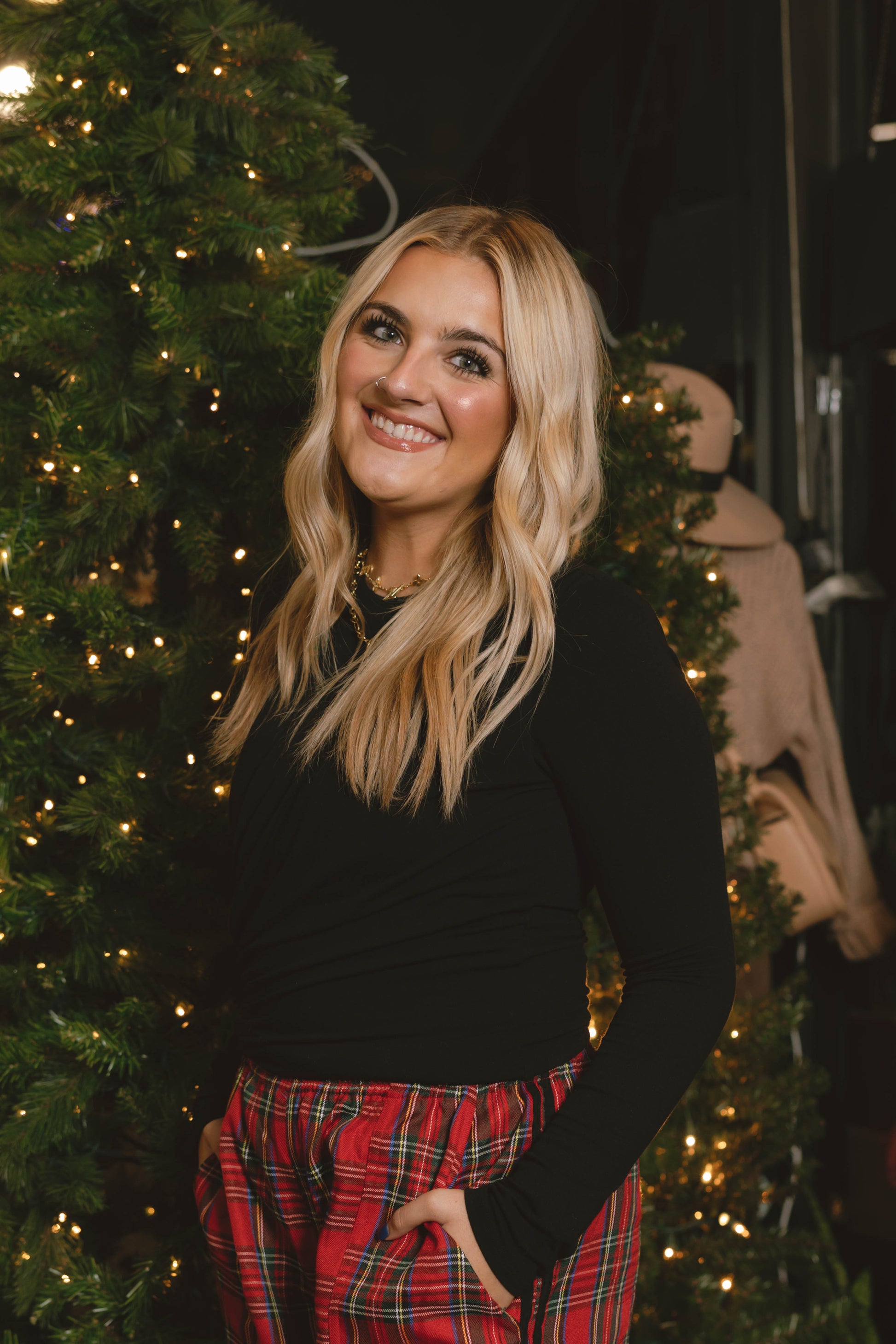 woman wearing black draped long sleeve top with red plaid holiday pants at Erin Rose Boutique.
