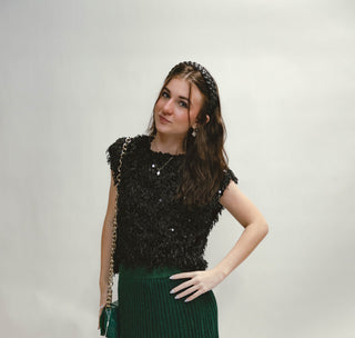 Woman wearing a black fringe sequin top on a white background