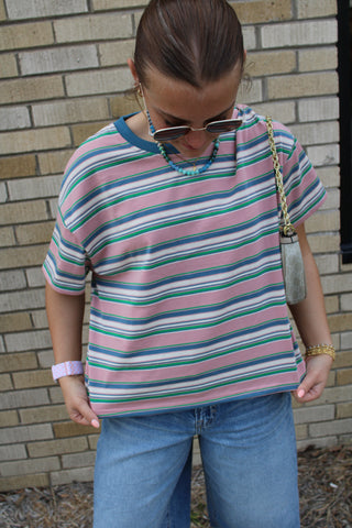 Person wearing a striped shirt and denim bermuda shorts 