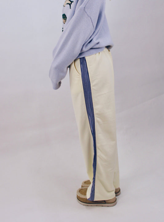 Woman wearing butter yellow wide leg pants with navy gingham side stripe detail styled with a lavender sweater.