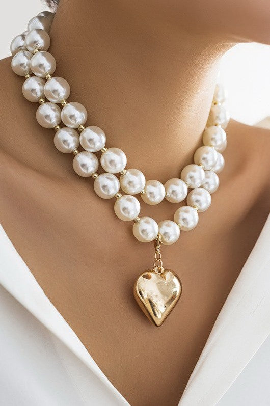 Pearl necklace with a gold heart pendant on a woman available at Erin Rose Boutique