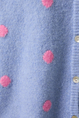 Close-up of a blue cardigan with pink polka dots and metal buttons.