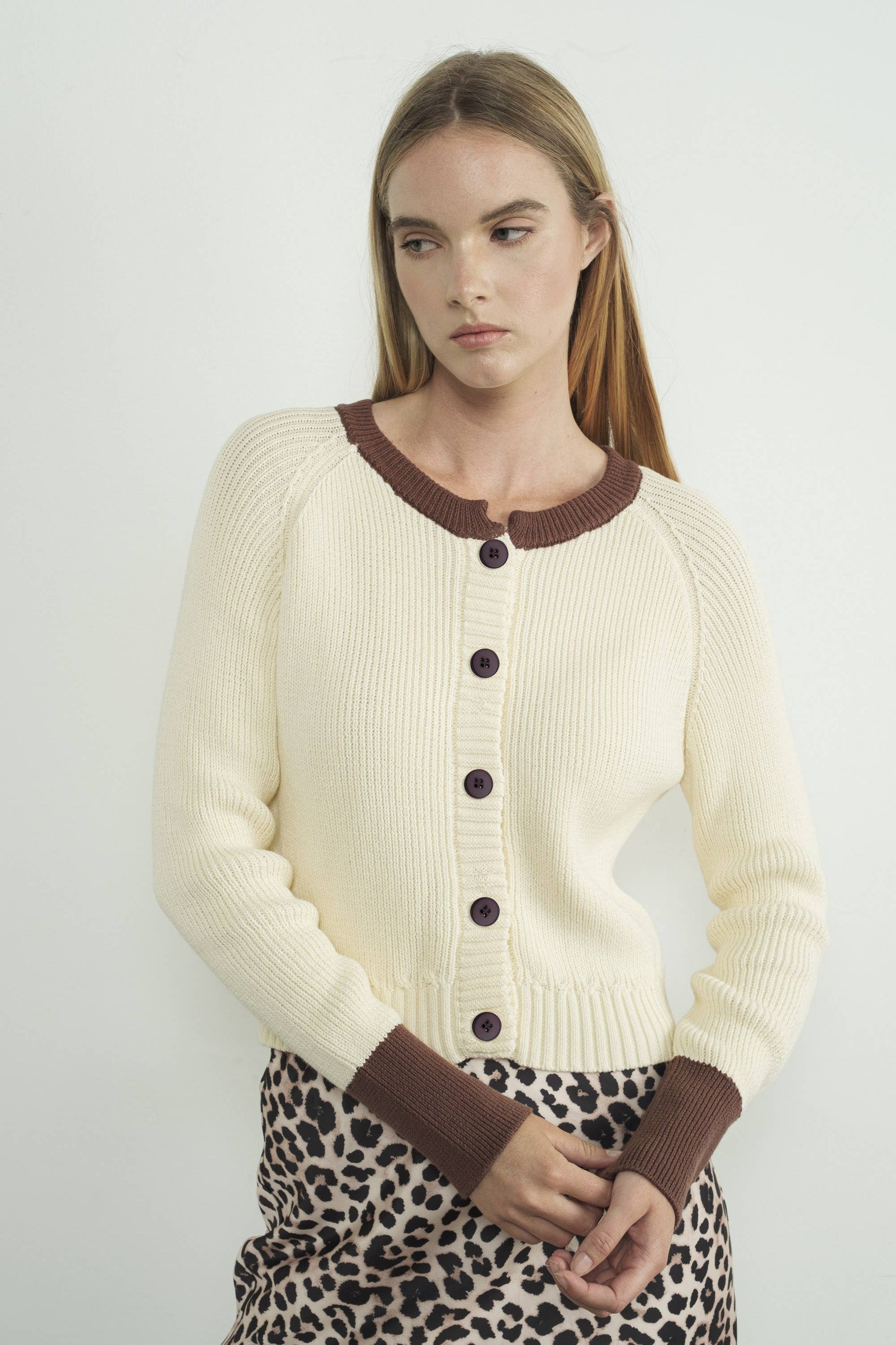 Woman wearing a cream cardigan with brown trim  available at Erin Rose Boutique