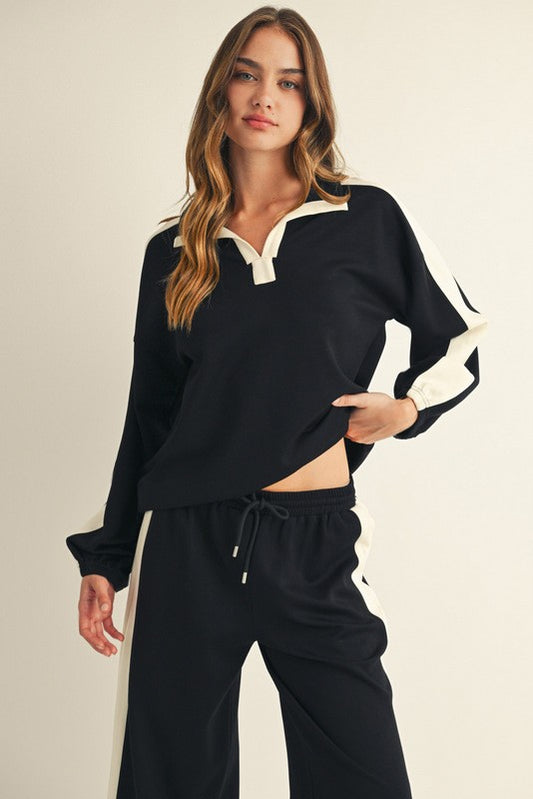 Woman wearing a black and ivory colorblock lounge Long Sleeve top with polo collar.  