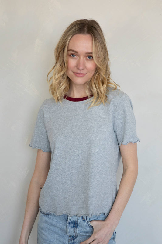 Woman wearing a gray t-shirt and blue jeans against a plain background at Erin Rose Boutique