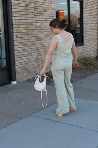 Person holding a white handbag on a sidewalk next to a building.