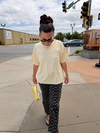 Oversized butter yellow striped short sleeve top styled for a casual summer look with polka dot pants and layered necklaces.