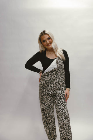 Person wearing leopard print overalls and a black long-sleeve shirt on a plain background available at ERB - Erin Rose Boutique