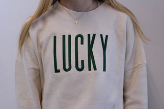 Beige sweatshirt with 'LUCKY' printed in green on a plain background