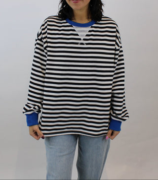 Person wearing a black and white striped shirt with blue sleeves against a plain background