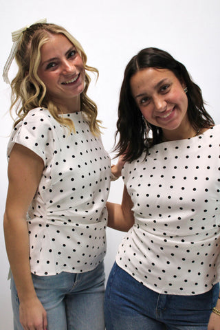 Two models wearing a cream short sleeve blouse with black polka dots, styled with denim jeans