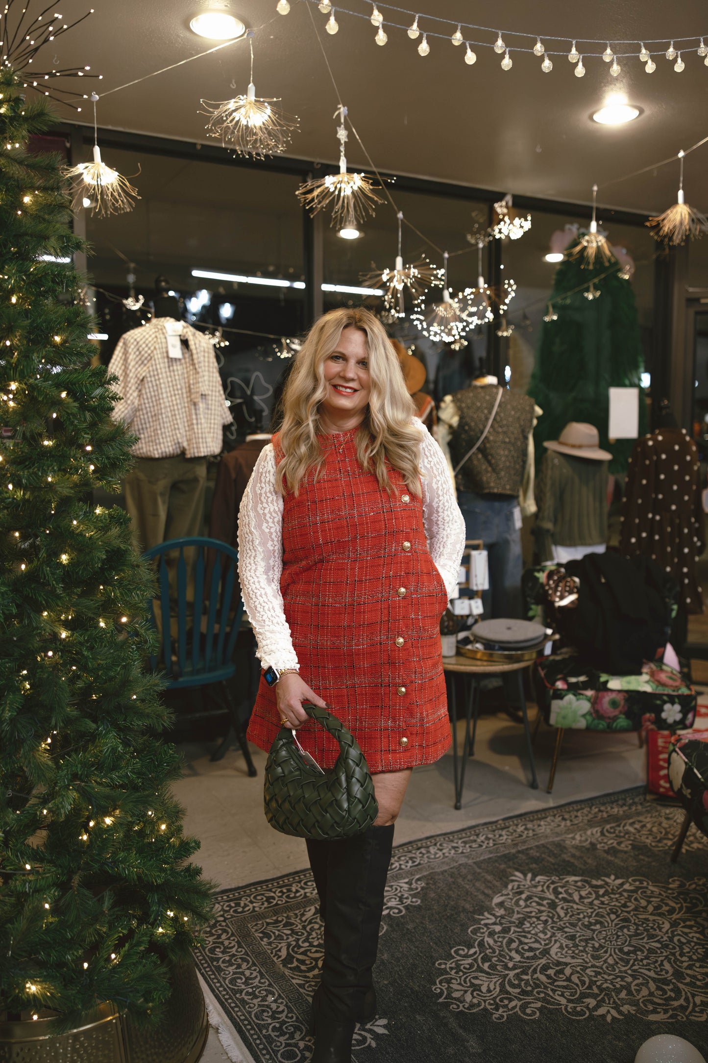 Woman in a red dress standing in a store decorated for Christmas.