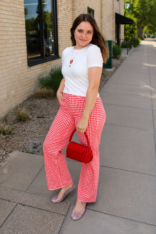 a woman wearing red gingham jeans styled with red handbag.
