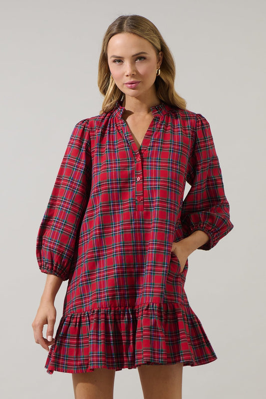Woman wearing a red plaid dress with long sleeves on a gray background