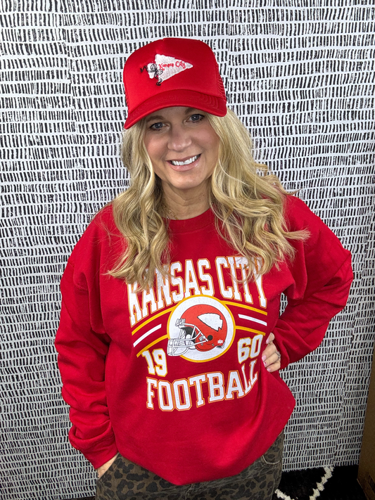 A person wearing a red sweatshirt with 'Kansas City Football 1960' text and a KC Chiefs helmet design.