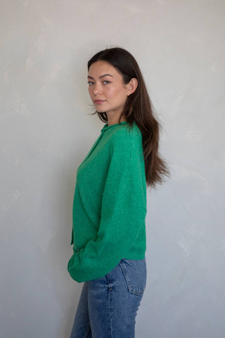 Side view of woman wearing a kelly green button-up knit Abby Rose piper cardi sweater styled casually with jeans at Erin Rose Boutique 