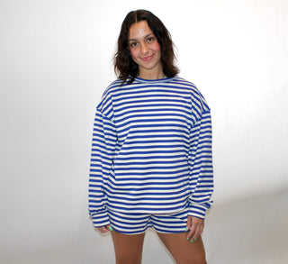 Model wearing a blue and white striped oversized long sleeve top with matching striped lounge shorts.