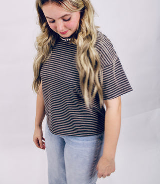 Woman wearing a striped shirt and light blue jeans on a plain background