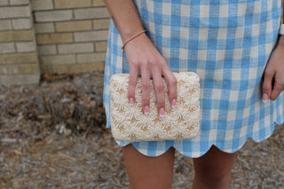 model holding woven neutral evening clutch bag styled with a gingham dress from Erin Rose Boutique