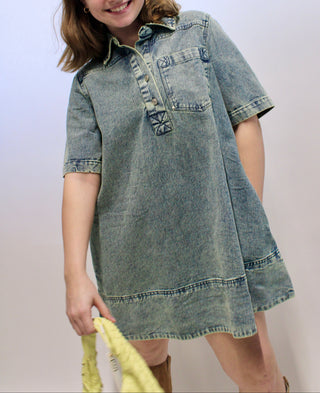 Child wearing a denim dress against a plain background