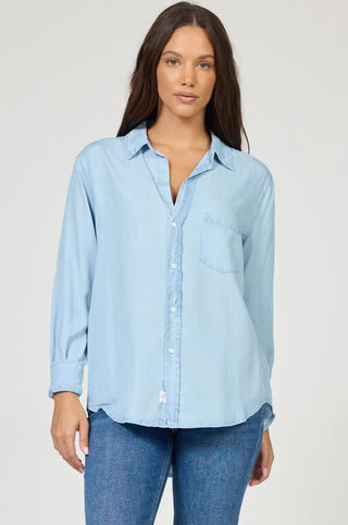 Woman wearing a light blue long sleeve button down shirt styled with blue jeans.
