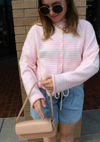 Baby pink and white striped lightweight cardigan with button front styled with denim shorts and a blush shoulder bag