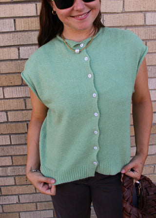 Woman wearing Abby Rose Piper matcha green button front knit vest cardigan with brown pants
