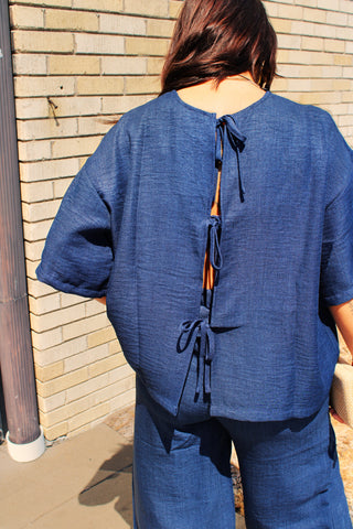 Back view of woman wearing navy relaxed fit tie back top with lightweight flowy fabric