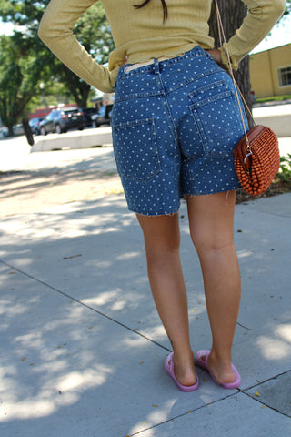 Back view of blue denim shorts with a white polka dot pattern.