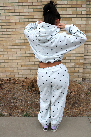 back view of woman wearing a heather grey hoodie with navy polka dots and matching sweatpants available at Erin Rose Boutique