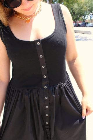 Boutique black sleeveless midi dress with a flowy skirt and front button detailing.