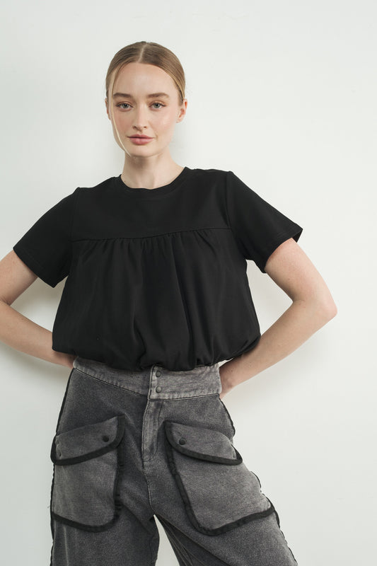 Woman wearing black short sleeve bubble hem top with gathered yoke detail