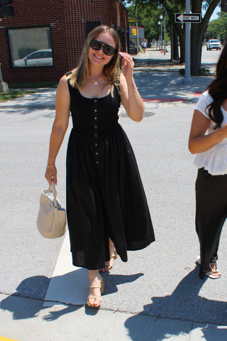 Classic black sleeveless midi dress with front button details styled with beige heels.
