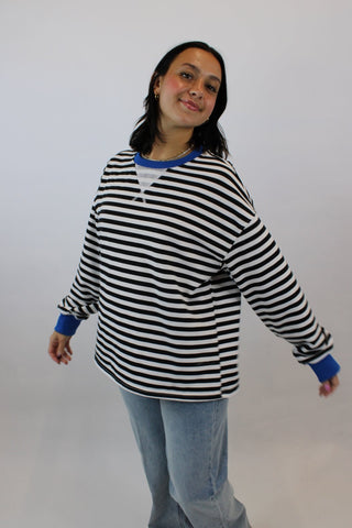 Person wearing a black and white striped sweater on a plain background