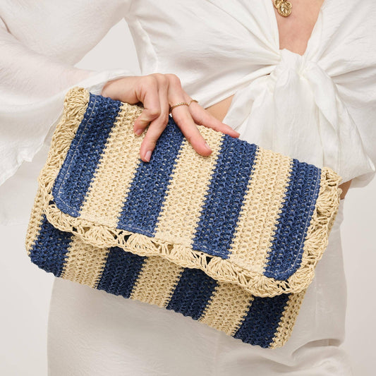 Woman holding a blue and beige striped straw clutch while wearing a white tied blouse – Erin Rose Boutique accessory